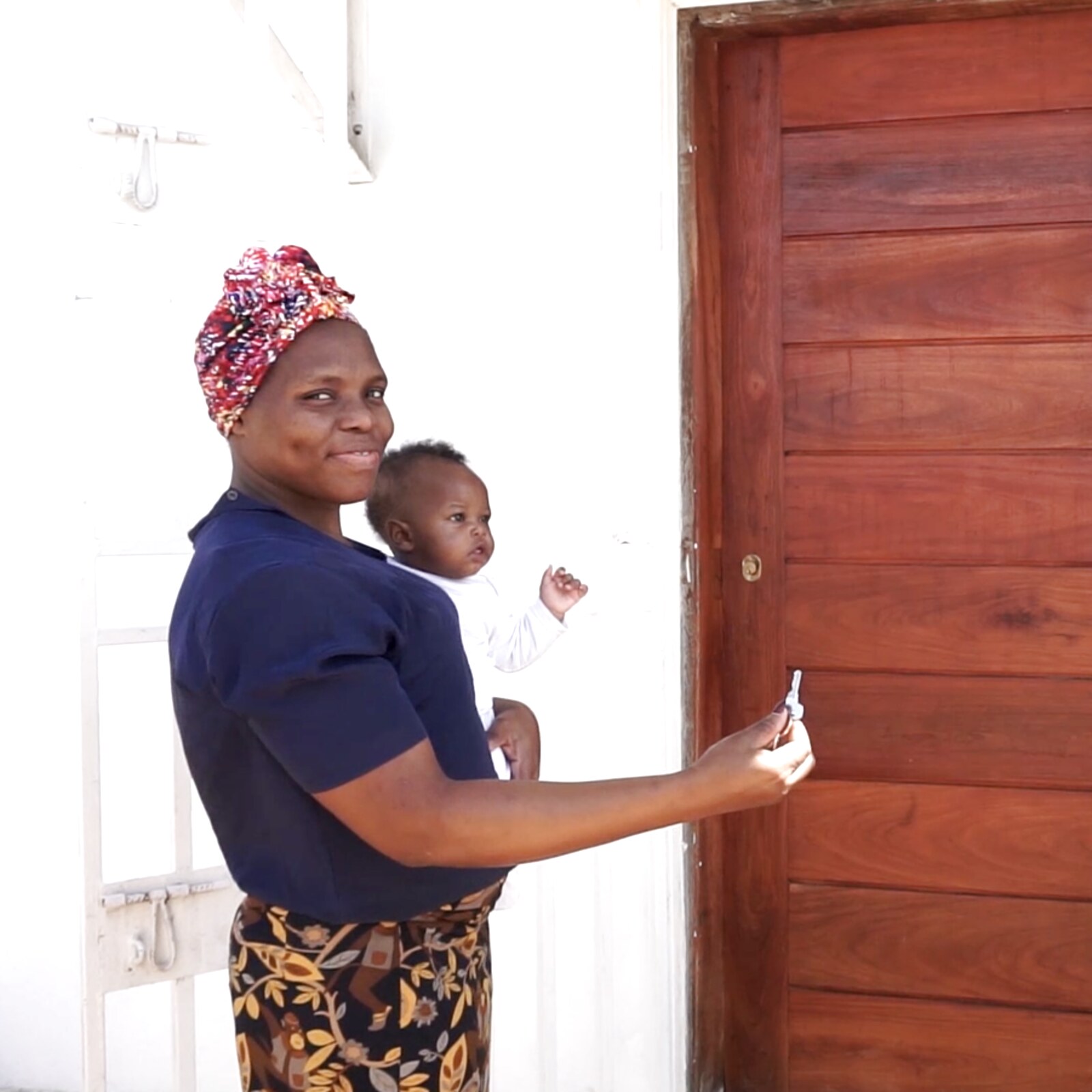 A mother holds her child and the keys to their new home in Mozambique.